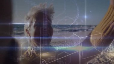 Kıdemli bir kadın kumsalda kolunu kaldırıyor yüzen teknoloji formülleri ve büyü ızgaralarıyla etkileşime geçiyor. Gelecekçi, yenilikçi, açık hava, teknoloji, dinginlik, keşif, sanal