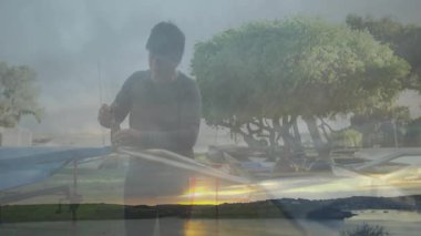 Kış gezisi panelindeki kano takımlarını animasyon harita simgeleriyle ayarlayan kıdemli bir kadın. Macera, açık hava eğlencesi, deniz, eğlence, doğa, sükunet, günbatımı.