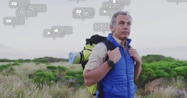 Olgun yürüyüşçü sahada duruyor, sırt çantası taşıyor, yüzen sosyal medya pazarlama simgeleri sergiliyor. Açık hava, macera, teknoloji, keşif, refah, bağlantı, doğa