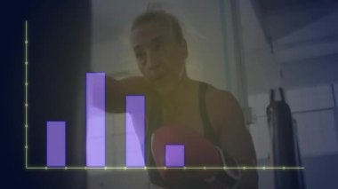 Spor salonunda ağır torba yumruklayan bir kadın, analitik testler için neon sarı çizelge sergiliyor. Atletik, kararlı, güçlü, enerjik, eğitimli, şehirli, motive edici