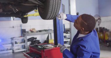 Otomotiv atölyesinde araba lastiklerini inceleyen kadın teknisyen animasyon grafikleri ve simgeleri kaplıyor. Endüstri, otomotiv, onarım, teknisyen, araç gereç, makine, bakım