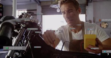 Otomotiv garajında motorsiklet kablolarını test eden erkek tamirci, yüzen kullanıcı simgeleri sergiliyor. Teknisyen, bakım, endüstriyel, teknoloji, mühendislik, atölye, araçlar