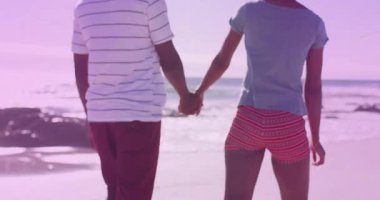 Sahilde el ele yürüyen bir çift. Yüzen kalp ikonu ve sağlık için nabız grafiği sergiliyorlar. Romantizm, arkadaşlık, rahatlık, dinginlik, doğal, enerjik, minimalist