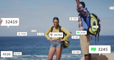 Okyanus kenarındaki uçurumları keşfeden iki gezgin seyahat teknolojisi için yüzen bildirim simgeleri gösteriyor. Macera, keşif, teknoloji, navigasyon, manzara, bağlantı, yoldaşlık