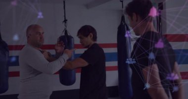 Koç, spor salonunda savunma talimi yapan öğrencilere rehberlik ediyor kum torbalarının yanında, ağ düğümleri gösteriyor. Uyarılar, fitness, eğitim, dijital, modern, güç, disiplin