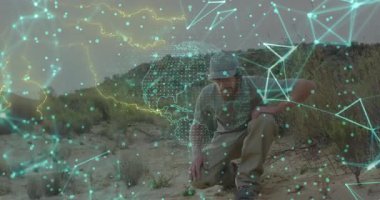 Alan araştırmacısı çöl temizliğinde diz çöküp toprağı inceliyor, parlayan teknoloji ağı verilerini gösteriyor. Açık hava, keşif, analitik, yenilik, çevre, keşif, görselleştirme