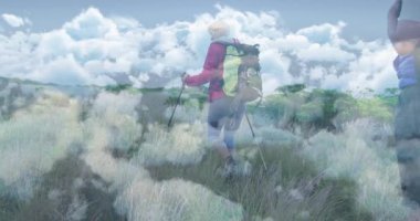 Yürüyüş direkleri kullanan kadın yürüyüşçü ve otlakta yürüyen erkek yürüyüşçü, seyahat verileriyle örtüşüyor. Macera, keşif, vahşi doğa, doğa, dayanıklılık, manzara