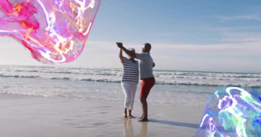 Adam kaykay üzerinde kadınla kıyıda dengede duruyor, parçacık girdaplarıyla teknolojiyi gösteriyor. Macera, takım çalışması, enerji, günbatımı, canlılık, kıyı, hareket