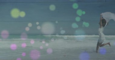 Okyanusun kenarında yalınayak dans eden kadın, sağlık için akıcı kumaş ve hareketli dalgalar sunuyor. Neşe, zarafet, sükunet, hareket, doğal, bohem, ışık