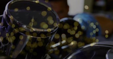 Tamirci mavi eldiven giyip otomobil atölyesinde üzerinde altın bokeh olan animasyon kaplamaları gösteriyor. Tamirci, otomotiv, tamirat, makine, sanayi, hassasiyet, güvenlik