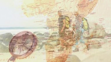 İki yürüyüşçü kayalık kıyı şeridinde yürüyor, Afrika haritasını ve eğitim için metal pusulayı sergiliyorlar. Macera, keşif, kıyı şeridi, açık hava, seyahat, navigasyon, engebeli