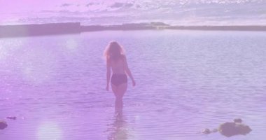 Sıcak bir parıltı altında kıyı sularına dalan bir kadın kalp atış hızı grafiğini kaplıyor. Huzur, sükunet, doğa, rahatlık, rahatlık, refah, minimalizm.