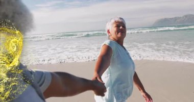 Sahilde yürüyen yaşlı bir kadın, sağlık reklamında ortağının elini tutuyor, altın parçacıklar fırıl fırıl dönüyor. Romantizm, arkadaşlık, huzur, uyum, canlılık, bağlantı, zarafet.