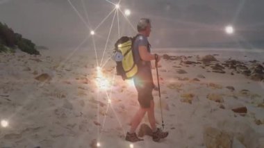Yürüyüşçü, kumsalda yürüyen yürüyüş direkleri kullanarak teknoloji ağı bağlantılarını gösteriyor. Macera, keşif, açık hava, engebeli doğa, bağlantı, dayanıklılık.