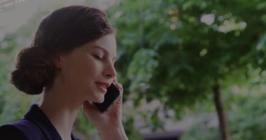 İş kadını açık havada akıllı telefondan konuşuyor. Teknolojik kodları gösteriyor. Yaprakların üzerinde süzülüyorlar. Profesyonel, bağlantı, modern, yenilik, kentsel, canlı, iletişim