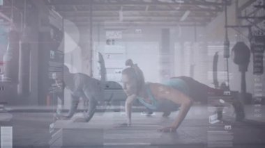 Endüstriyel spor salonunda senkronize şınav çeken erkek ve kadın yüzen performans çizelgeleri sergiliyorlar. Fitness, egzersiz, güç, eğitim, hareket, modern, kararlılık