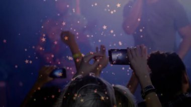 Seyirciler müzik etkinliği sırasında akıllı telefonlar kaldırırken, yıldız şeklindeki bokeh animasyon enerjisi yayıyor. Konser, sahne, atmosfer, performans, gece hayatı, aydınlanma, kalabalık