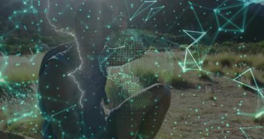 Erkek sporcu çimenli alanda diz çöküp hologram küresi ve teknoloji gösterimindeki düğümlerle etkileşime giriyor. Gelecekçi, yenilikçi, açık hava, teknoloji, dijital, manzara, etkin