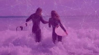 Çift el ele tutuşuyor, sörf yapıyor, sörf tahtası taşıyor, kalp ikonu sergiliyor. Macera, dostluk, kıyı şeridi, boş zaman, açık hava, canlılık, uyum.