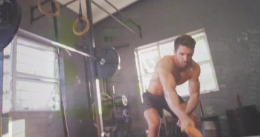 Erkek fitness meraklısı, spor salonundaki traktör lastiğine balyoz sallıyor ve animasyon ağırlık simgeleri gösteriyor. Atletik, güçlü, eğitimli, endüstriyel, dinamik, kaslı, egzersiz