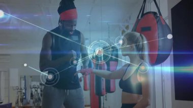 Kadın müşteri ve erkek antrenör spor salonunda yumruk tokuşturuyor, holografik ağ örtüsü sergiliyorlar. Fitness, koçluk, antrenman, kardiyo, güç, motivasyon, dijital