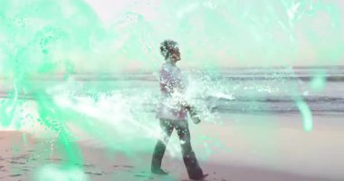 Kıdemli kadın kumlu sahil şeridinde yürüyor, deniz mavisi teknolojisi veri parçacıkları gösteriyor. Emeklilik, sağlık, dinginlik, macera, dijital sanat, manzara, boş zaman