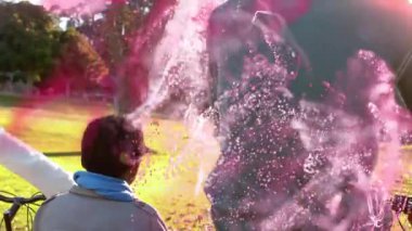 Baba, oğlunu bisikletle parkta tutuyor. Pazarlama için pembe parçacıklar gösteriyor. Aile, açık hava, canlı, neşeli, bağlayıcı, doğal, sıcak.