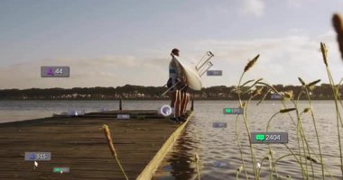 Göl kenarı rıhtımında yarış kabuğu taşıyan kürekçiler sosyal medya simgelerini gösteriyor. Atletizm, takım çalışması, doğa, açık hava, motivasyon, spor, işbirliği