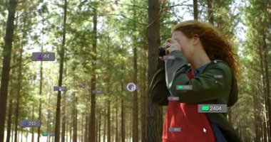 Çam ormanlarında dijital pazarlama için yüzen ikonlarla birlikte DSLR kamera kullanan kadın fotoğrafçı. Doğa, açık hava, vahşi doğa, macera, teknoloji, sosyal medya, keşif