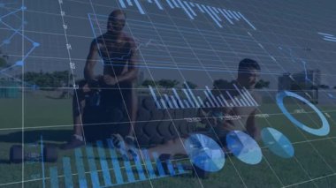 Yüzen fitness teknisyenleri ve turta grafikleriyle çimenli spor sahasında dinlenen iki erkek sporcu. Fitness, takım çalışması, açık hava, modern, zindelik, sağlık, yenilik