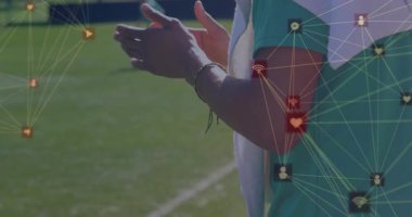 Koç, futbolcular sahada top sürerken alkışlıyor, sosyal medya pazarlama simgeleri parlıyor. Atletik, takım çalışması, dijital, canlı, motivasyon, eğitim, sportmenlik