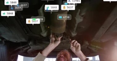 Tamirci oto tamirhanesinde araba şasisini ayarlıyor, yüzen beğenileri ve konum simgelerini gösteriyor. Otomotiv, teknisyen, sanayi, bakım, mühendislik, tanı, profesyonel