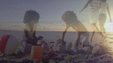 Seyahat pazarlaması için sahilde aile kumdan kalesi inşa ediyoruz. İçinde yüzen kova ve kürek ikonları var. Tatil, boş zaman, açık hava, yaşam tarzı, eğlence, sıcak, neşeli