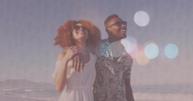 Güneşli sahilde dikilen çift, animasyon pazarlama grafikleri ve dijital telefon ikonları paylaşıyor. Romantizm, eğlence, yaşam tarzı, dinginlik, canlı, açık hava, mutluluk.