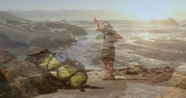 Sırt çantası ve dalgaların yanındaki kayalık sahilde kucaklaşan erkek ve kadın. Animasyon seyahat haritası eşliğinde. Macera, yürüyüş, romantizm, açık hava, gün batımı, sahil, keşif