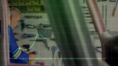 Otomotiv tamirhanesinde çalışan tamirci, elektrik matkabını ızgara ve grafiklerle birlikte tahta tahta tutuyor. Sanayi, zanaat, kesinlik, teknik bakım, araçlar, çalışma alanı