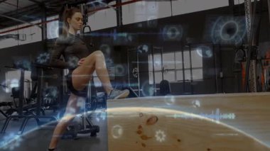 Spor salonunda bacağını plüyometrik kutuya dayayan bir kadın, yüzen fitness teknolojisi ve hologramları gösteriyor. Fitness, antrenman, yenilik, dijital, güç, egzersiz, modern