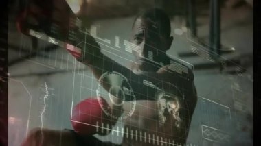 Erkek boksör spor salonunun içindeki odaklanma eldivenlerine yumruk atıyor. Teknolojik holografik çizelgeler ve dünya haritası kullanıyor. Sporcu, fitness, inovasyon, eğitim, arayüz, güç, rekabet