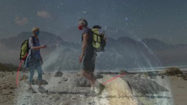 Kadın yürüyüşçü ve erkek yürüyüşçü Rocky Sahili 'nde dijital teknolojiyle yumruk tokuşturuyorlar. Macera, keşif, açık hava, engebeli gece manzarası, seyahat, yürüyüş