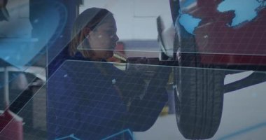 Otomobil tamiri sırasında kaldırılmış arabanın altında pnömatik ingiliz anahtarı kullanan kadın bir tamirci. Otomotiv, onarım, işçilik, sanayi, teknisyen, atölye, makine