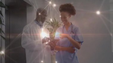 Erkek doktor, hastane koridorunda hemşireyle tableti işaret ederek sağlık ağı düğümlerini gösteriyor. Tıbbi, takım çalışması, modern, teknoloji, işbirliği, yenilik, profesyonel