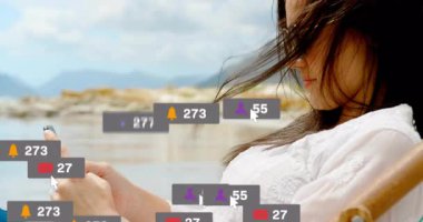 Gölün kenarında akıllı telefon kullanan bir kadın, yüzen sosyal medya bildirimleri sergiliyor, teknoloji odaklı. Rahatlama, açık hava, rahatlama, doğal, minimalist, dinginlik, bant genişliği