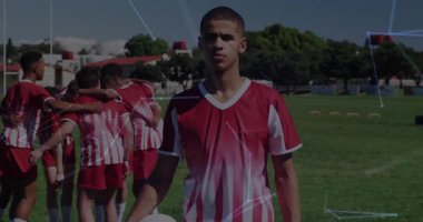 Genç futbolcu sahada duruyor, takım arkadaşları toplanıyor, ağ izleme verilerini örtüyor. Sporcular, takım çalışması, açık hava, atletizm, eğitim, gençlik, direniş