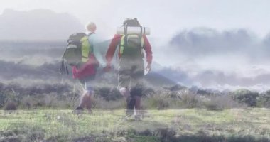 Olgun bir çift, sisli tepelerde yürüyüp yüzen kalp atış hızı ikonunu ve adım sayısını gösteriyor. Macera, keşif, sükunet, doğa, açık hava, sağlık, yolculuk