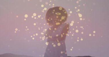 Kadın alacakaranlıkta tepede duruyor, yüzen altın ışıklarla sağlık uygulaması konseptini sergiliyor. Mistik, zarafet, dinginlik, alacakaranlık, rüya gibi, düşünceli, ambiyans