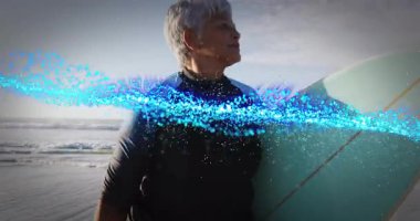 Sahilde elinde sörf tahtası olan bir kadın, teknolojiyi gösteren dönen dijital parçacıklar taşıyor. Macera, canlılık, sağlık, esneklik, güçlenme, teknoloji, dinamik