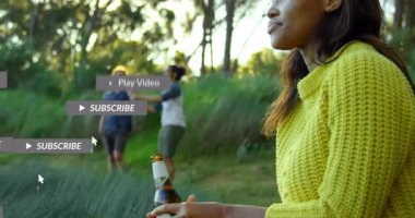 Arkadaşları parkta yürüyor ve şişe içiyor, yüzen sosyal medya pazarlama grafikleri sergiliyor. Açık hava, grup, eğlence, doğa, bağlantı, gençlik, gündelik