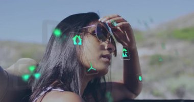 Kadın arabanın camına yaslanmış, enerji pazarlaması için karbondioksitli yüzen yeşil eko ikonlar gösteriyor. Macera, sürdürülebilirlik, rahatlık, çevre dostu, açık hava, modern, huzur