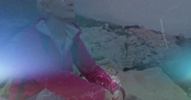 Dağ zirvesinde meditasyon yapan kadın yürüyüşçü, sağlık verilerini gösteren bir kablo çerçevesi ile. Macera, sükunet, farkındalık, vahşi doğa, keşif, esneklik, alpler.