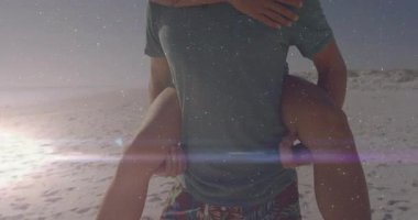 Sahilde gün batımında kadın sırtında taşıyan bir adam kalp ikonu ve çizelgesini gösteren bir teknoloji sergiliyor. Romantizm, açık hava, eğlence, macera, neşeli, manzaralı, eğlenceli